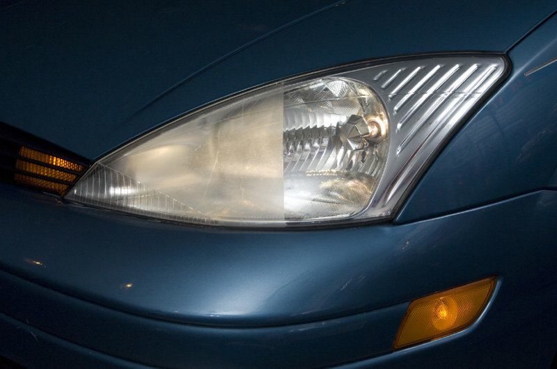 Faro con una mitad opaca y otra mitad restaurada en un auto azul: reparación de faros de auto